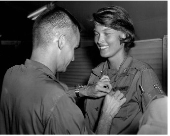 Photo of Cammermeyer receiving medal from someone important. The other person is pinning the award to the shirt pocket while Cammermeyer smiles.